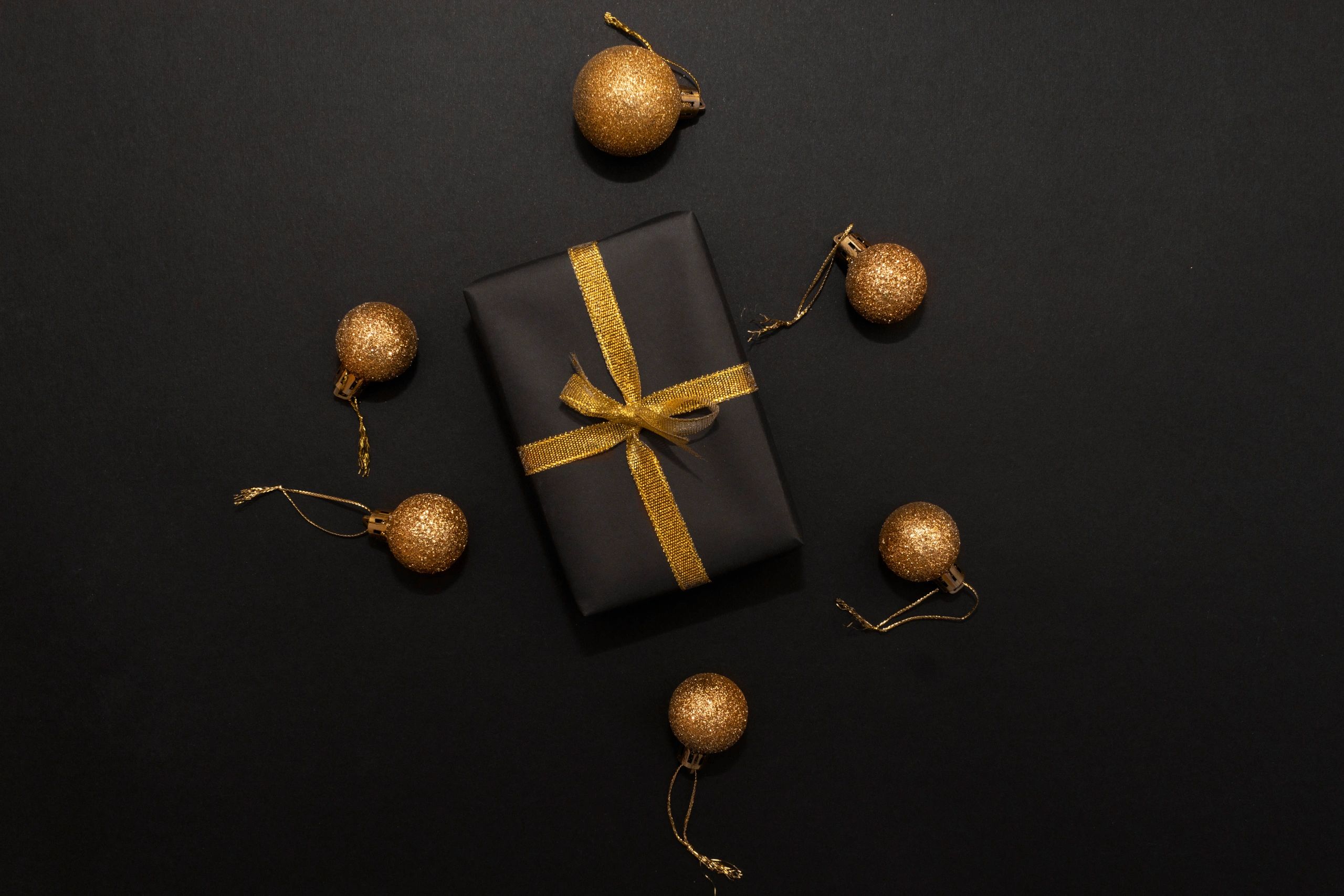 Black gift box with gold ribbon on dark background